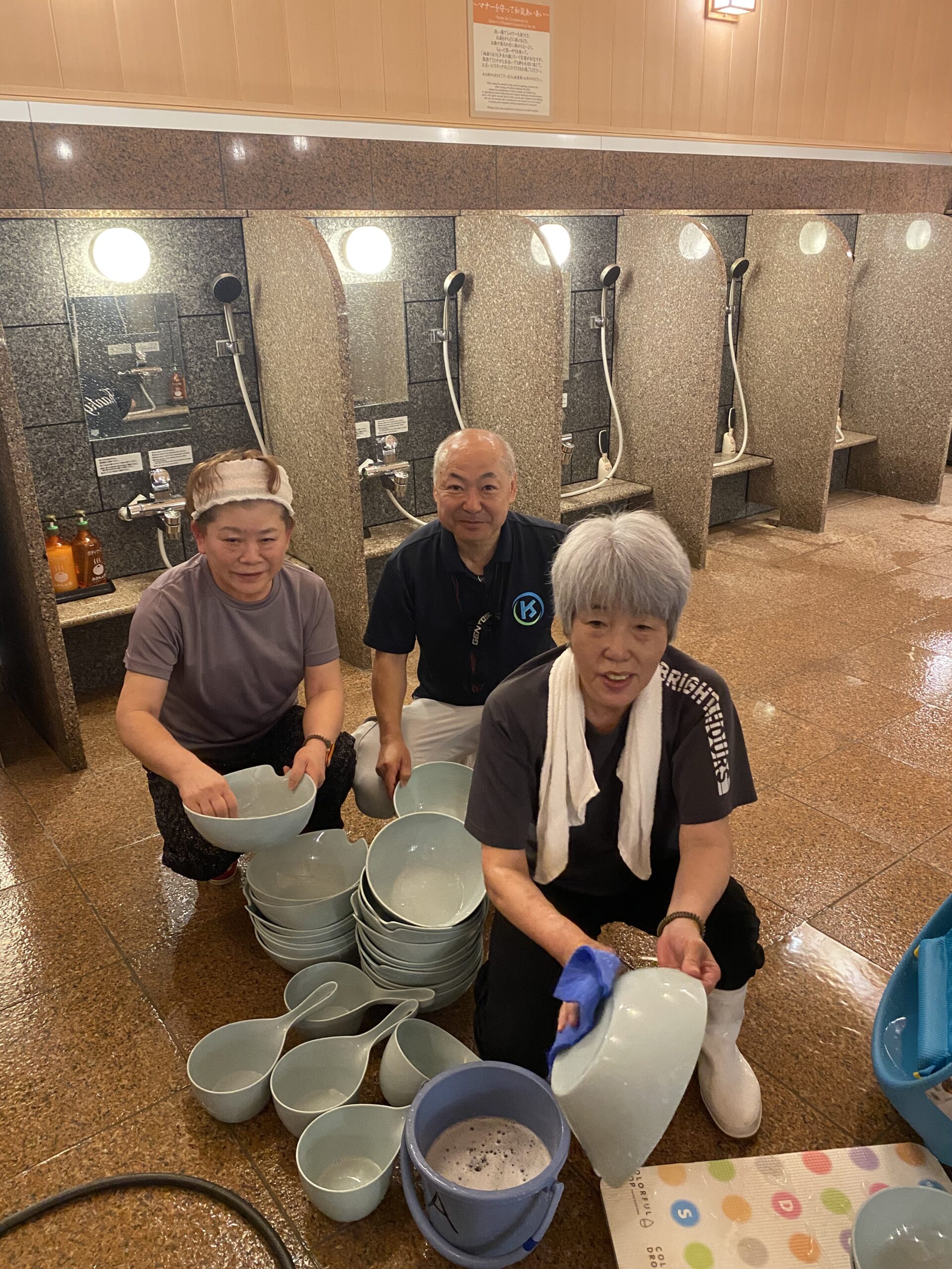 みかんの湯様の洗い場で洗面器を清掃するスタッフ